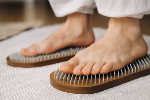 The man's feet are next to boards with nails. Yoga classes photo