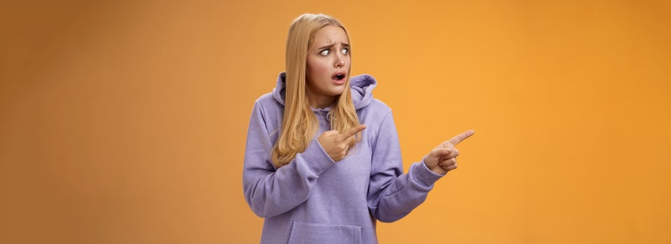 Concerned freak-out panicking funny blond girl gasping pop eyes drop jaw pointing left shocked stunned terrible scene friends boyfriend kissing anoyed standing upset and disappointed photo