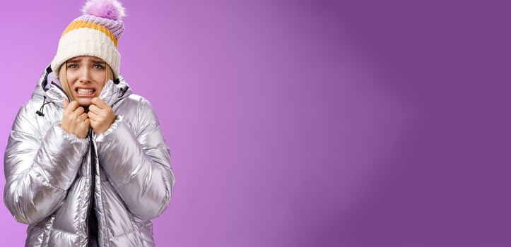 Uncomfortable shaking displeased charming gloomy blond cute woman in silver stylish jacket pulling coat tight wear hat shaking clenching teeth grimacing suffering low temperature freezing cold photo