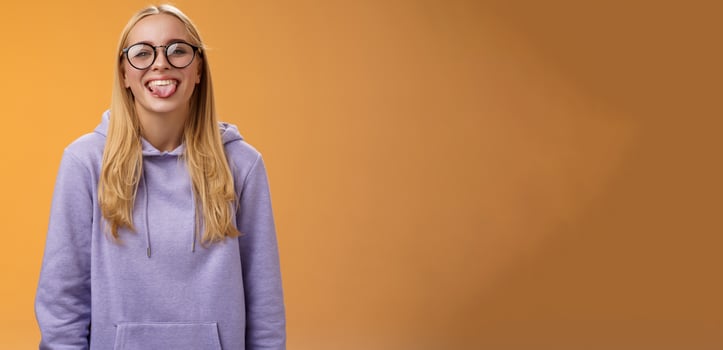 Funny charming female programmer having fun show tongue fool around coworkers during lunch break smiling broadly laughing in cute glasses purple hoodie, standing purple background photo