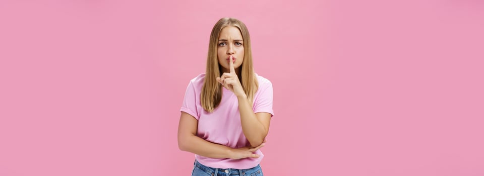 Shh keep voice down. Serious-looking concerned determined female nanny looking after kid asking not speak showing shush gesture with index finger over mouth, having secret concerned someone know it photo