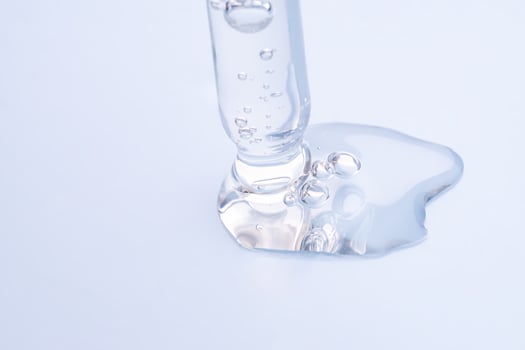 Liquid hyaluronic gel or serum on a screen of microscope blue isolated background photo