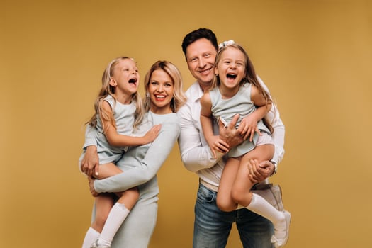 Happy parents hold their children in their arms and smile on a yellow background. an emotional family of four photo