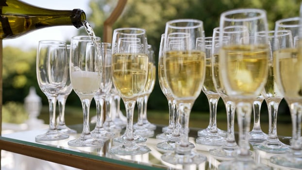Champagne spilling at a dinner party. The server pours champagne. Catering at the event. A waiter pours champagne and glasses in the outdoor greeting area. Champagne celebration. photo