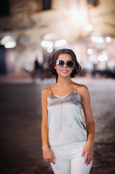 a girl in trousers and a t-shirt with glasses in the night city of San Gimignano.A girl walks around the city in Italy.Tuscany. photo