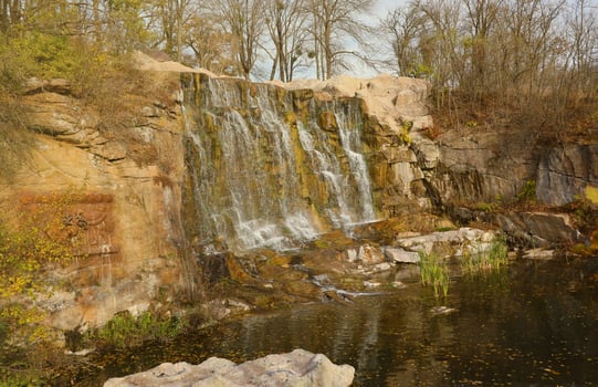 Beautiful waterfall between large rocks in autumn forest. Sofievskiy park in Uman, Ukraine photo