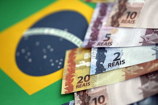 Brazilian money bills on top of the national flag of Federative Republic of Brazil photo