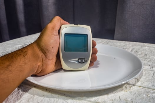 hand holding a test tool for blood glucose, cholesterol and uric acid levels on a dinner plate photo