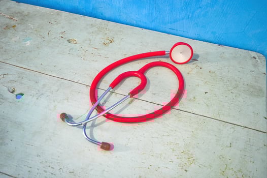 A red stethoscope on a wooden table photo