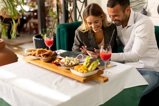Young coupleusing mobile phone while having lunch and drinking fresh squeezed juice in the restaurant photo