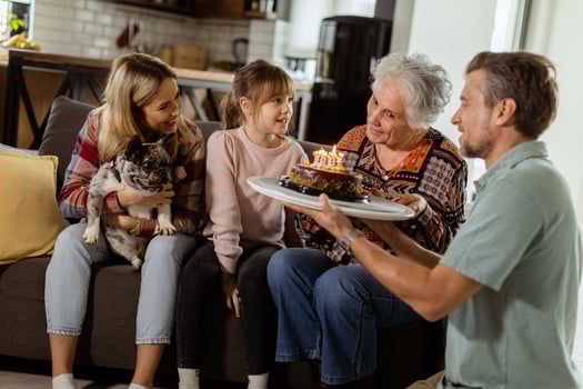 Joyous Family Celebrating Grandmothers Birthday With Cake in a Cozy Living Room photo