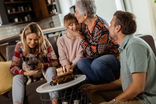 Joyous Family Celebrating Grandmothers Birthday With Cake in a Cozy Living Room photo