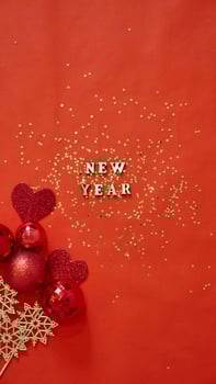 Christmas flatley with New Year lettering on red gold background baubles decoration. Close-up, shiny composition. Postcard . Vertical photo