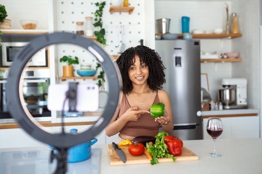 Young African American woman cooking speaker talking on digital camera recording vlog. African woman vlogger or shooting blog filming reportage advertising video, coaching. photo