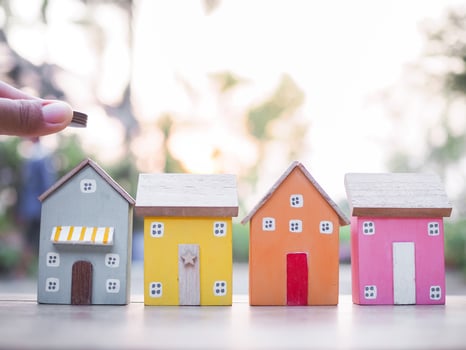 Close up hand putting coin with miniature house. The concept of saving money for house, Property investment, House mortgage, Real estate. photo