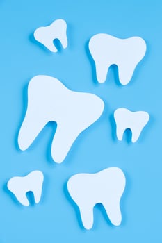 Paper cut mockup of tooth on blue background. Dental care concept. International Dentist Day. photo