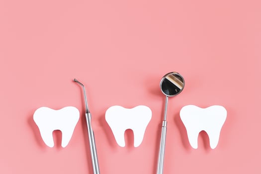 Dental care concept. Dental tools on pink background. Happy dentist day. Paper cut mockup of tooth. photo