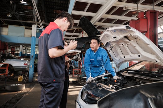 Asian male professional automotive engineer supervisor describes car engine maintenance and repair work with mechanic worker staffs team in fix service garage, specialist occupations in auto industry. photo