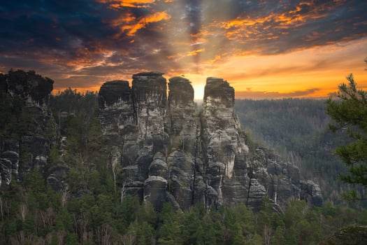 Rugged rocks at Basteibridge at sunset. Wide view over trees and mountains. photo
