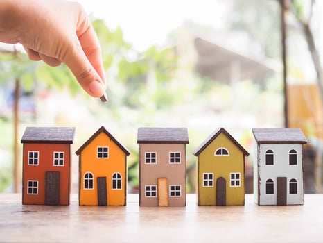 Close up hand putting coin with miniature house. The concept of saving money for house, Property investment, House mortgage, Real estate. photo