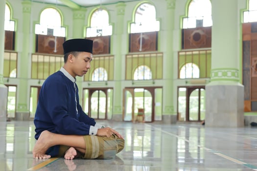 Portrait of religious Asian man in muslim shirt praying and doing salat or sholat in mosque photo