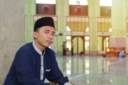 Portrait of religious Asian man in muslim shirt sitting in mosque photo