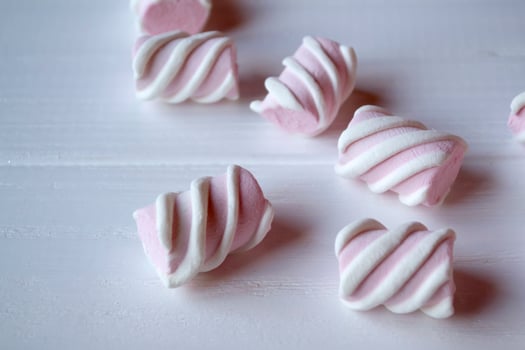 Pink marshmallow on a white wooden table. photo