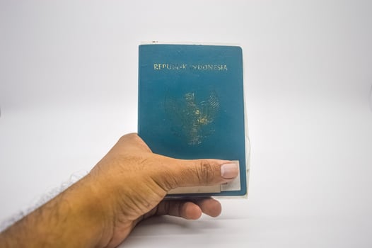 hand holding an Indonesian passport isolated on a white background, Indonesia, 2 January 2024. photo