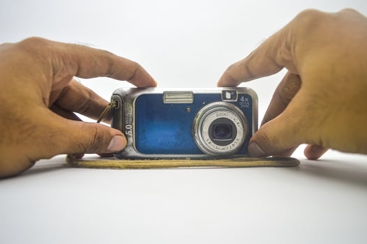 hand holding an old school pocket camera like a selfie isolated on white background photo