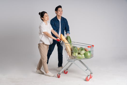 Image of Asian couple pushing supermarket cart while shopping, isolated on white background photo