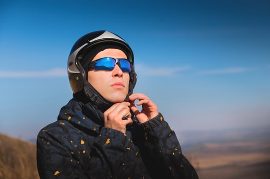 A young male paraglider in sunglasses fastens his helmet on a sunny day. Preparing for paragliding photo
