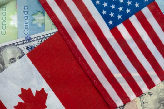 United States and Canadian flags on dollar and loonie currencies photo