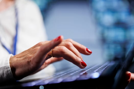 Computer scientist in data center working on laptop, setting up high bandwidth dedicated multiplayer gaming servers to accommodate more traffic from worldwide locations and avoid lag, close up photo