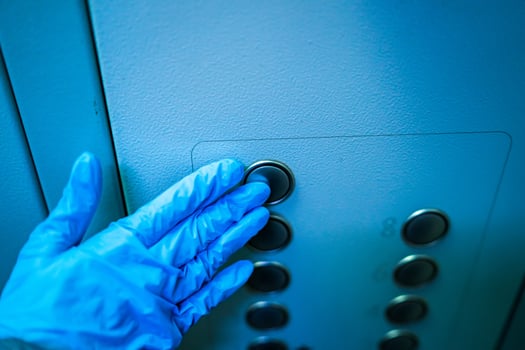 Man presses elevator button during flu covid virus outbreak. Blue gloves in hands. Coronovirus epidemic. Pneumonia. COVID-19 and coronavirus. Pandemic. photo