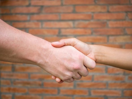Close-up of shaking hands between man and woman with a brick background. Concept of partnership and teamwork photo