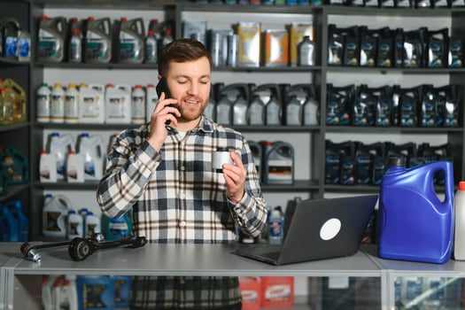 A salesman in an auto parts store is talking to a customer on the phone photo