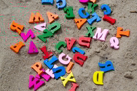 Multicolor wooden letters on a sand close up. photo