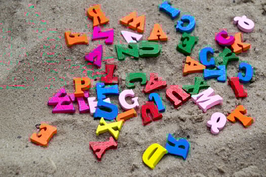 Multicolor wooden letters on a sand close up. photo