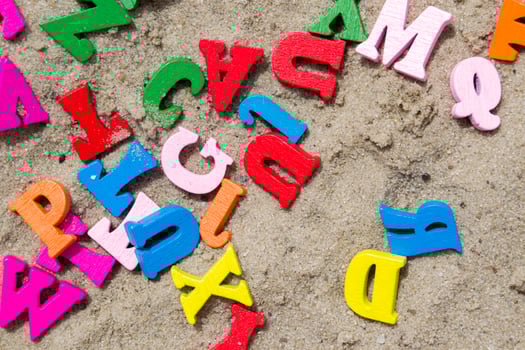Multicolor wooden letters on a sand close up. photo