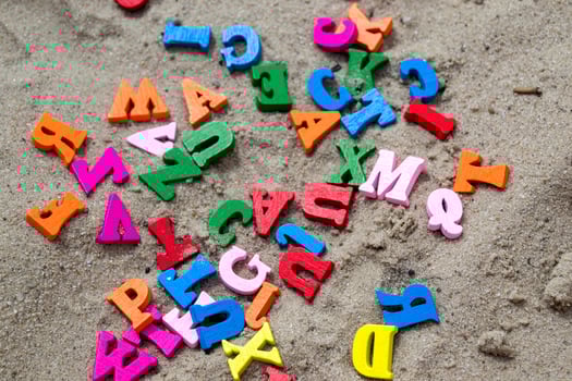 Multicolor wooden letters on a sand close up. photo