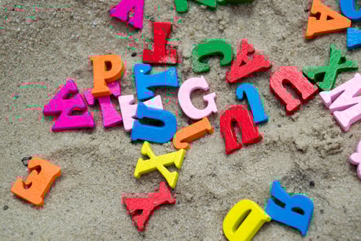Multicolor wooden letters on a sand close up. photo