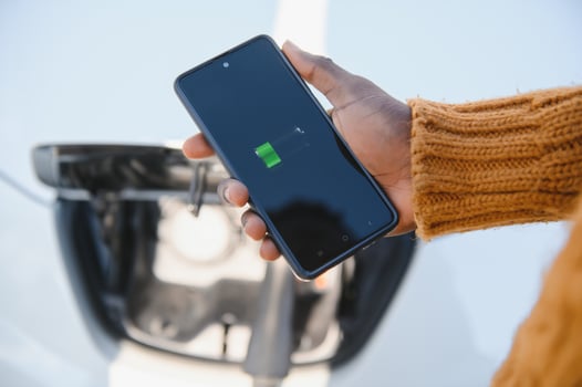 Smartphone app shows charging status of the electric car battery. Electro transport concept photo