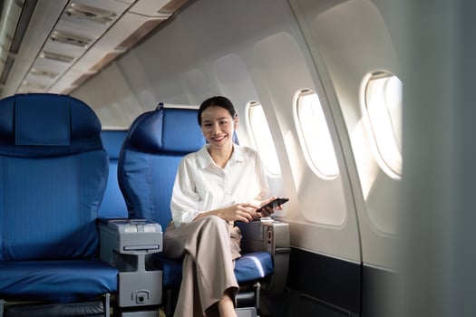 Traveling and technology. Flying at first class. Young business woman passenger using smartphone while sitting in airplane flight photo