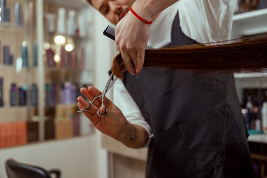 Closeup of hairdresser hands holding a comb while cutting hair of woman photo