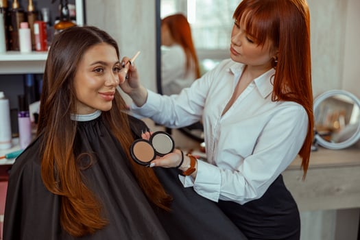Professional makeup artist doing makeup with a brush in beauty salon photo