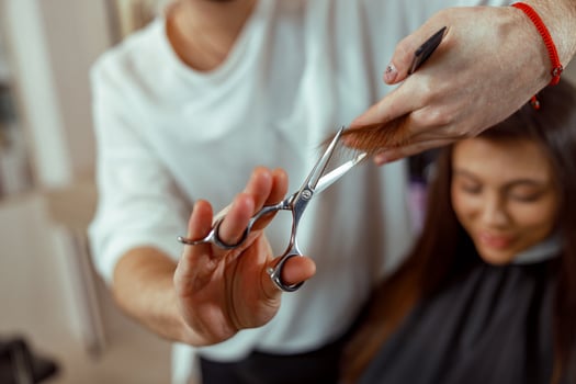 Hairdresser holding scissors in his hands and cutting client hair photo