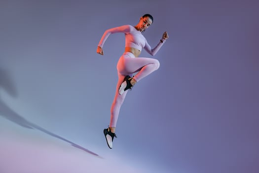 Attractive sporty woman in sportswear jumping on studio background. Sport and healthy lifestyle photo