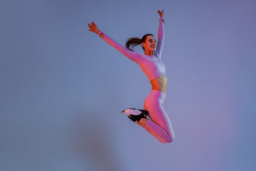 Smiling sporty woman in sportswear jumping on studio background. Sport and healthy lifestyle photo