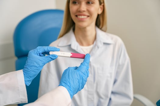 Female doctor hand showing positive pregnancy test for a pregnant woman at medical clinic photo
