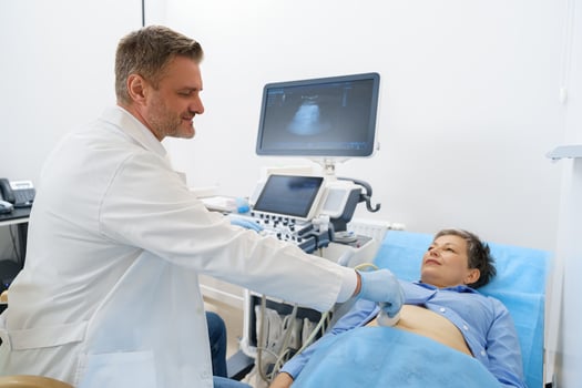 Male sonographer doing abdominal ultrasound scanning for woman patient in medical clinic photo